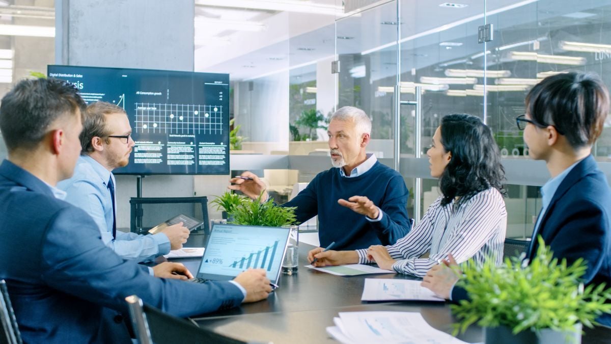 Professional people in a conference room reviewing revenue cycle analytics data on a screen