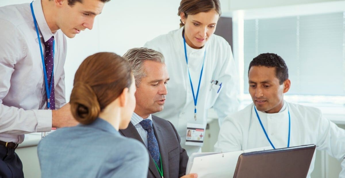 Hospital administrators and finance staff reviewing data with healthcare workers in a meeting room